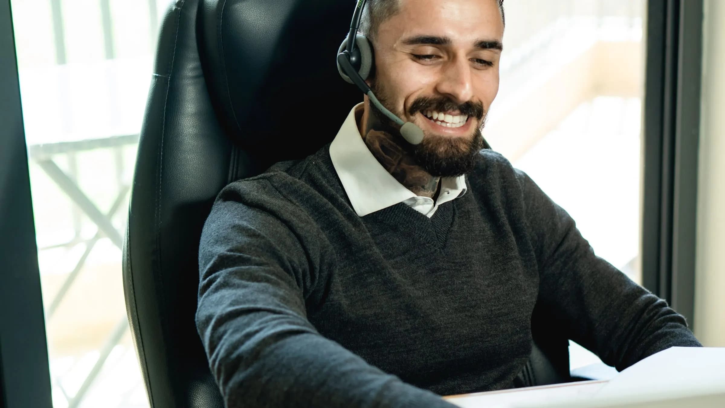 A support engineer wearing a headset, working at a laptop.