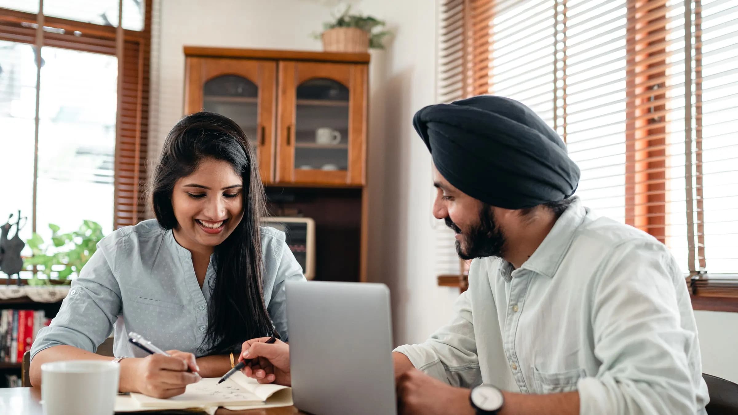 Two people going through a project brief at a table, one taking notes and one at a laptop.